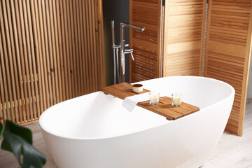 Tub and wooden folding screen in bathroom, closeup. Interior design