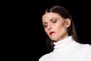 Serious woman looking down in dramatic studio portrait
