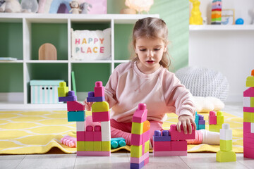 Little girl playing with toys on floor in playroom