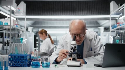 Portrait of joyous researcher analyzing genetic samples with high tech microscopic equipment in laboratory. Cheerful senior man doing biotechnology advancement discovery in research clinic, camera A - Powered by Adobe