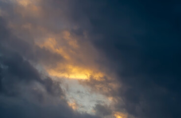 Ciemne chmury dominują na zimowym niebie w miarę zbliżania się wieczoru, a ich fragmenty rozświetla złociste światło słoneczne. Kontrast między ciemnymi i jasnymi obszarami tworzy dramatyzm i nastr&oacute;j