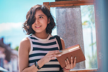 Young woman, take a book from a box of books on the street, she is standing on the sidewalk.