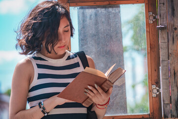 Young woman, take a book from a box of books on the street, she is standing on the sidewalk.