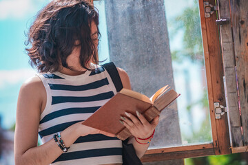 Young woman, take a book from a box of books on the street, she is standing on the sidewalk.