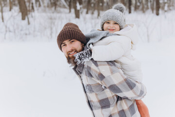 Father piggybacking daughter enjoying winter snow playtime