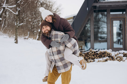 Happy couple enjoying piggyback ride in winter snow