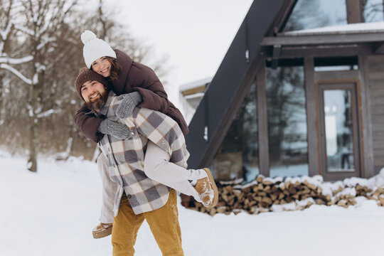 Happy couple enjoying piggyback ride in winter landscape