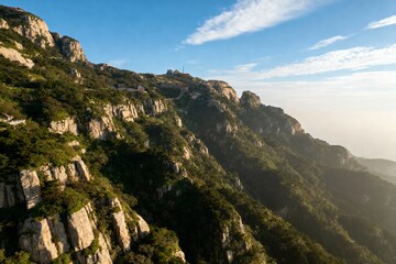 Rugged mountain range with rocky cliffs and lush greenery under a clear blue sky