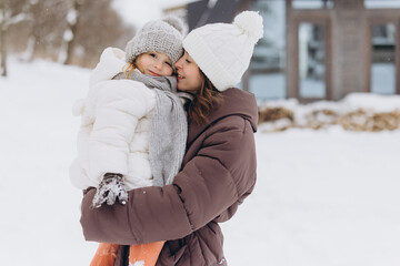 Mother and daughter embracing outdoors in snow