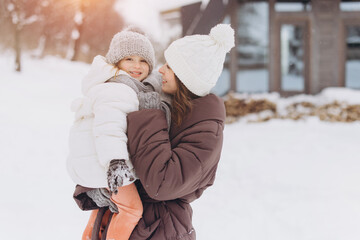 Mother holding daughter smiling enjoying winter snow day