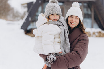 Mother holding daughter smiling enjoying winter snow day