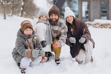 Family celebrating winter holiday with sparklers in snow