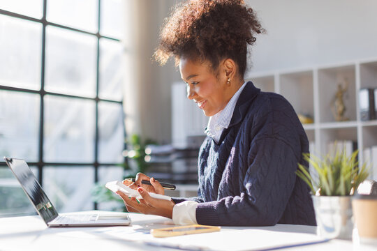 Business in afro hair businesswoman using calculator to calculate and record company marketing data.Finance, accounting and planning, budget management, income and expenditure.
