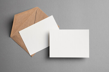 Blank double paper cards mockup with a brown envelope on a gray background, showcasing design options for invitations, greetings, or personal messages with copy space