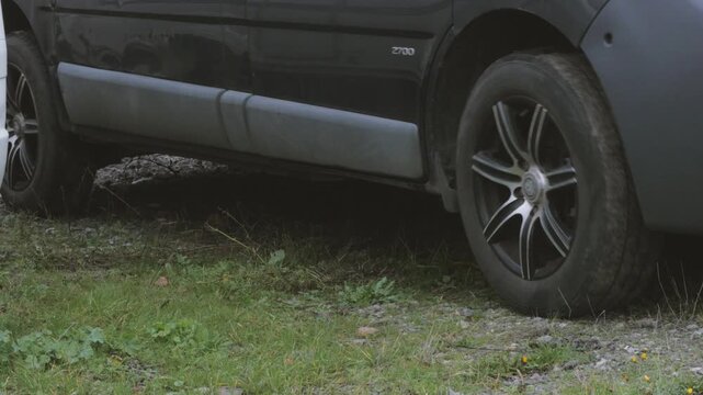 mid sized panel van vehicle, close up wheels, slowly pulls away on gravel surface, engine revving sound