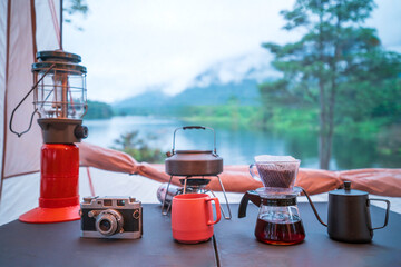Coffee drip set for camping inside a tent, looking out to the mountain and lake view.