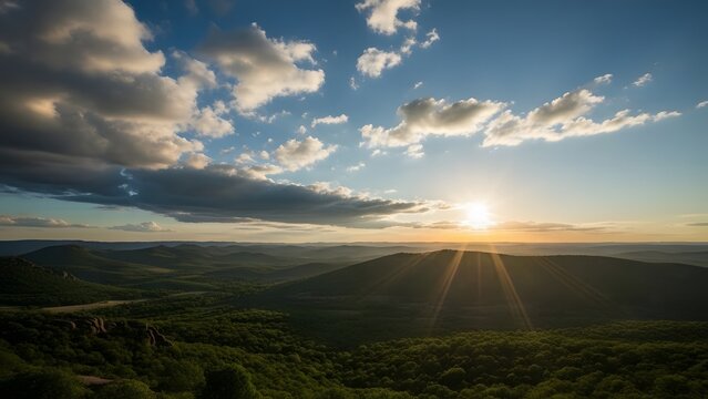 Breathtaking aerial view of a vibrant sunset over lush green mountain ranges with dramatic sunbeams and cloudy skies. - Powered by Adobe