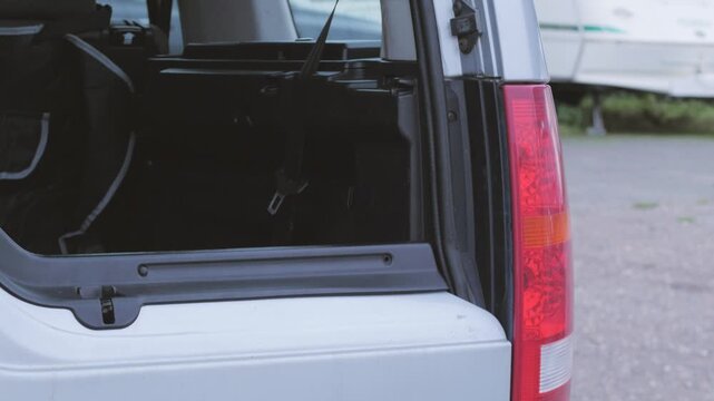 Close up opening SUV split tailgate, boot or trunk, lifting door, sound of catch and gas strut, shuffling feet, sync audio