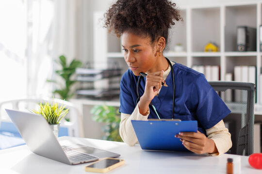 Nurse, young female doctor using laptop online, writing notes in medical journal sitting at desk, professional medic physician working on computer at workplace, med student learning, planning

