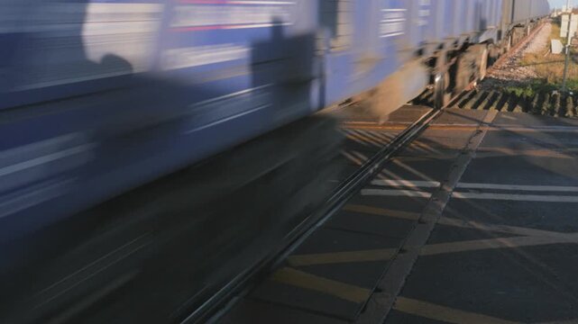 procession of long train of goods carriages passing over level crossing, close up wheels, clears frame, loud rattling sync sound audio