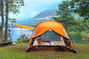 A summer camping tent set in a green mountain forest under the open sky