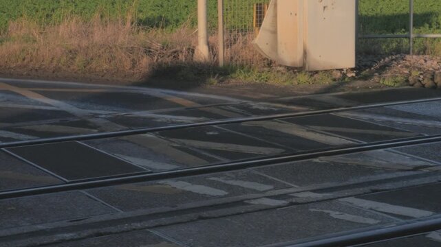 small silver hatchback car drives over railroad crossing aka railway level crossing, close up wheels, UK drives on left side of road, sync audio sound