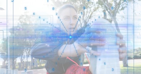 Assisting fitness trainer in red leggings supporting raised leg in park, showing AR overlay