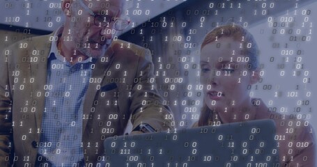 Pointing man in glasses and woman in dark blazer viewing laptop in office, showing binary overlay