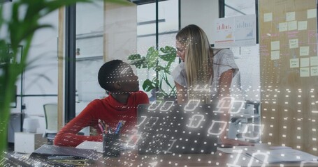 Collaborating two women in red sweater and light blouse discussing project at office, with laptop