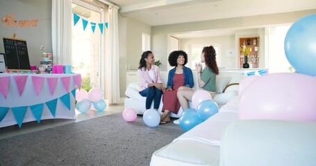 Chatting three women in pink, red, green sitting on white sofa in living room, bunting, balloons