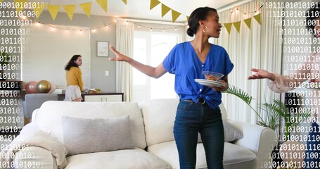 Gesturing woman in bright blue blouse holding plates and bowl at home living room, with bunting