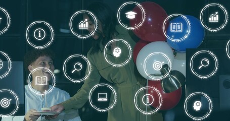 Leaning coworkers at office desk, olive dress holding candle-topped cupcake, HUD icons and balloons