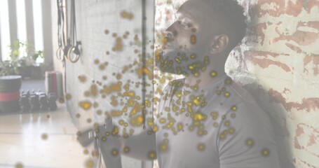 Leaning man in fitted athletic clothes holding cable at brick wall in fitness studio, copy space