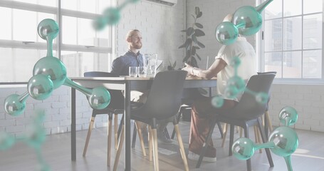 Talking colleagues in navy shirt and light top at sunlit office table with teal molecular overlays