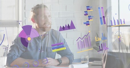 Presenting bearded man in button-up shirt explaining digital charts at meeting desk with monitor