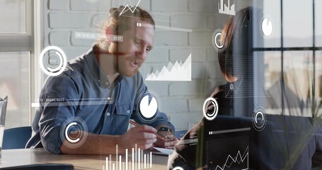 Writing bearded man in muted top leaning speaking in office with notebook, laptop, holographic UI