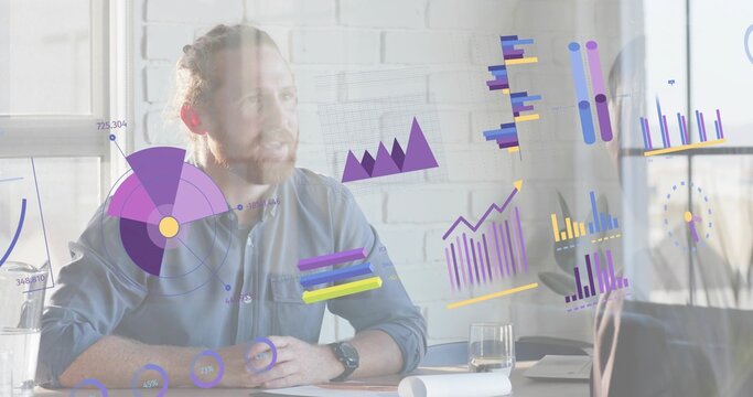 Presenting bearded man in button-up shirt explaining digital charts at meeting desk with monitor - Powered by Adobe