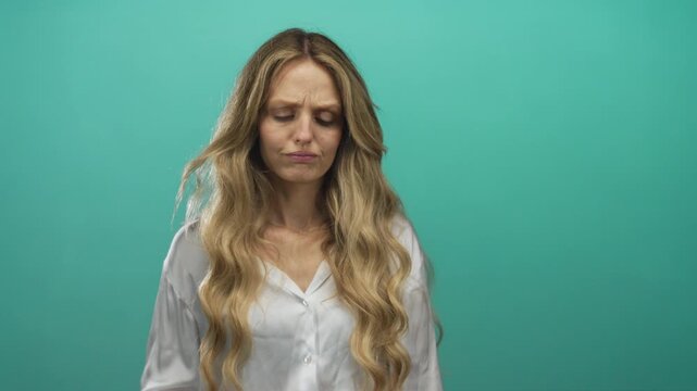 Woman showing frustration with hand on forehead against green background conveying stress and emotion in isolated setting