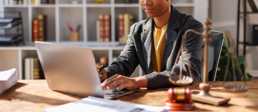 A woman in afro hair paralegal immersed in work at a law office, surrounded by paperwork and legal documents.
