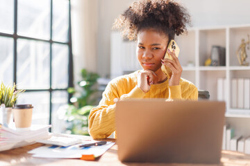 Business woman using laptop calling phone at office desk. talking smartphone read financial graph chart Planning marketing info. Happy African american in afro hair business people work office firm