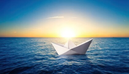 Obraz premium Paper boat sailing on the ocean at sunset, a symbol of hope.