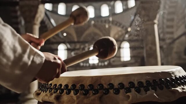 Warm, close-up hands striking the traditional bedug drum break the spiritual prison of silence.