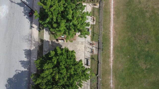 Drone 4K top-down aerial view of a public playground inside a neighborhood park. The scene emphasizes outdoor recreation, green spaces and community wellbeing, reflecting everyday urban life and healt