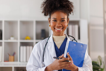 Portrait of female African American in afro hair doctor standing in her office at clinic
