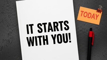Bold Black Text "IT STARTS WITH YOU!" Printed on White Paper Alongside a Small Orange Sticky Note