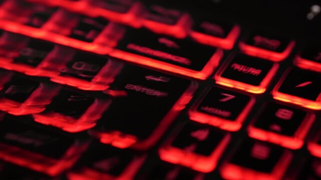 Abstract red data light streaks created by fast zoom motion over a backlit keyboard, focusing on the Enter key. Futuristic technology background.