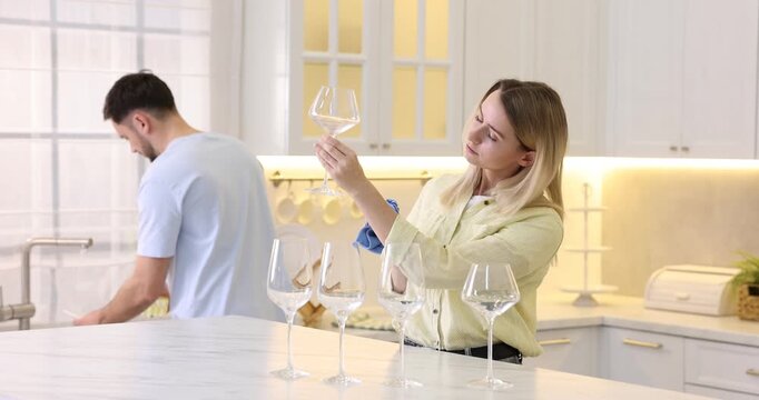 Couple wiping tableware together in kitchen. Domestic chores