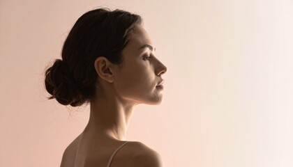 Close-up profile of a young woman with her hair pulled back in a bun, against a soft, diffused background