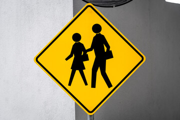 Yellow sign warning of a pedestrian crossing mounted on a concrete wall © Hamilton Productions