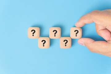Wooden cube block shape with sign question mark symbol on blue background